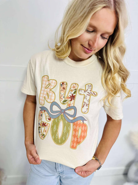 Woman wearing a cream t-shirt with colorful text design against a white background