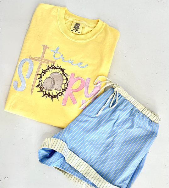 Yellow t-shirt with 'true story' text and blue shorts on a light gray background